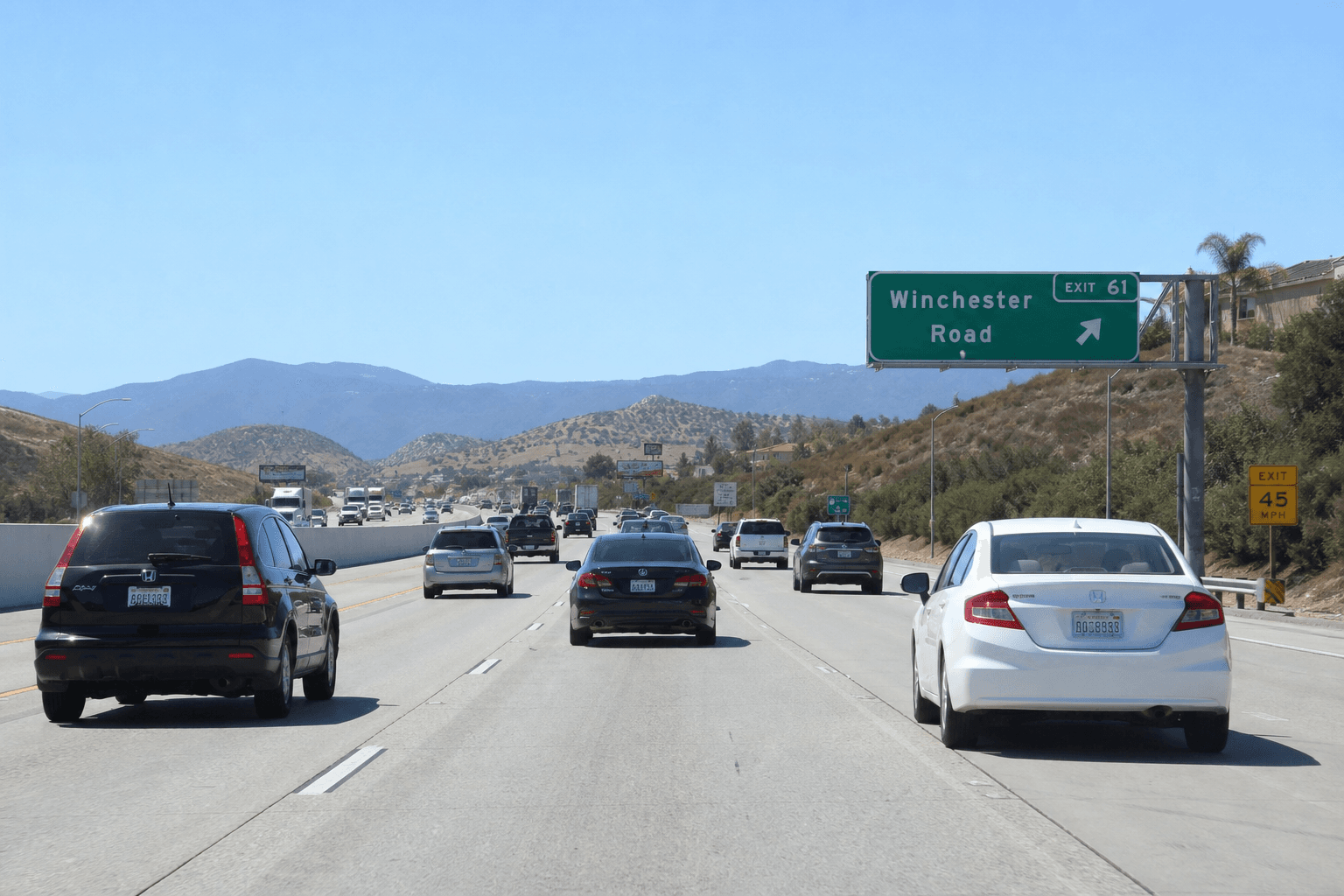 Northbound I-15 traffic backed up near Winchester Road in Temecula under a bright sky.