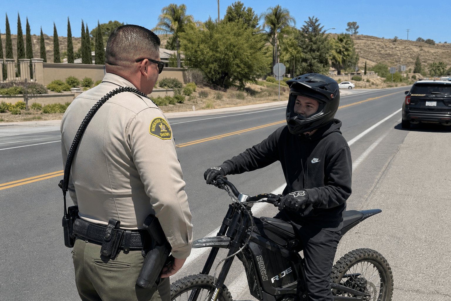 A sheriff's deputy conducting a traffic stop of a young rider on an electric off-road motorcycle on a Temecula street.
